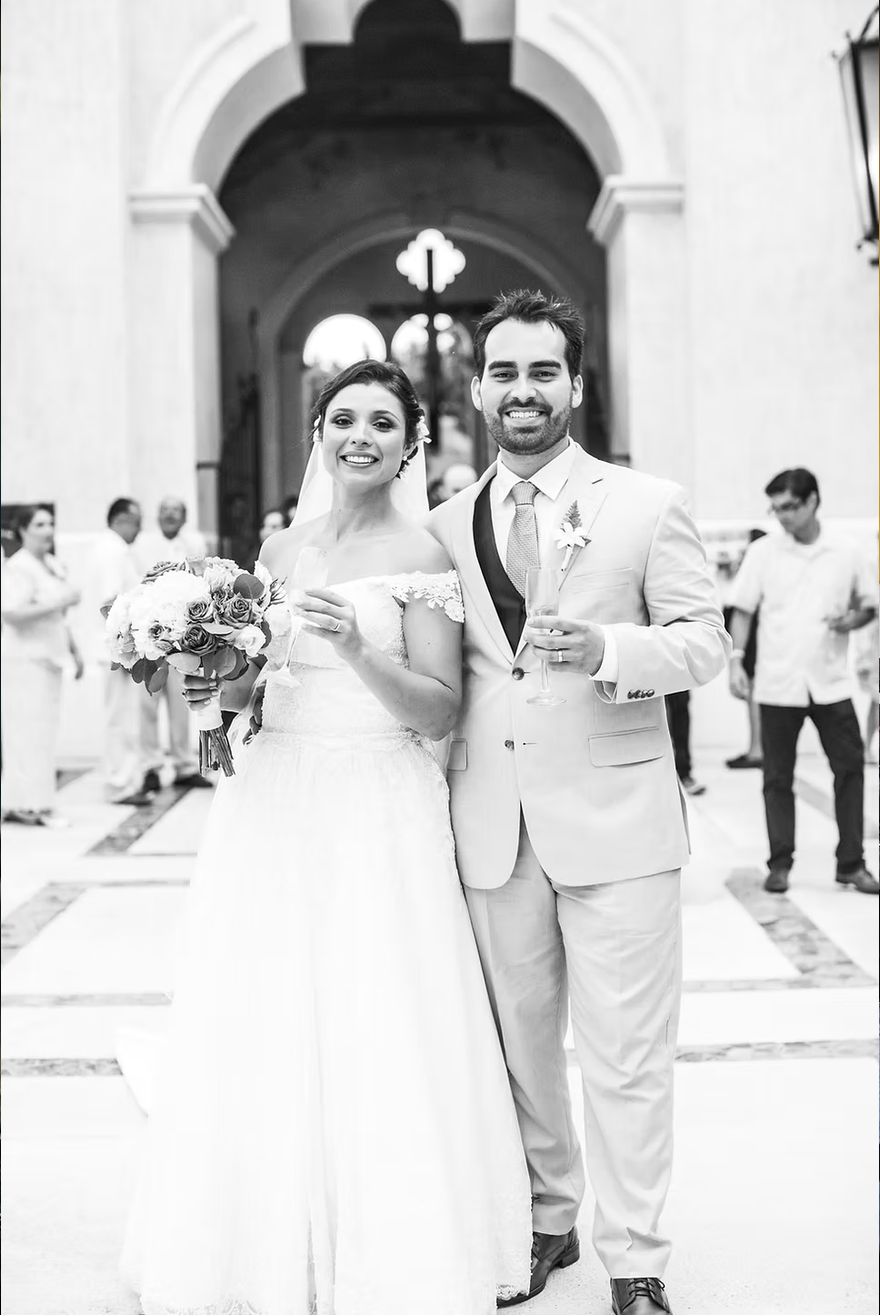 Black and white photo of a newlywed couple toasting with champagne outside a Mexican church — destination wedding photography by Murrieta Media